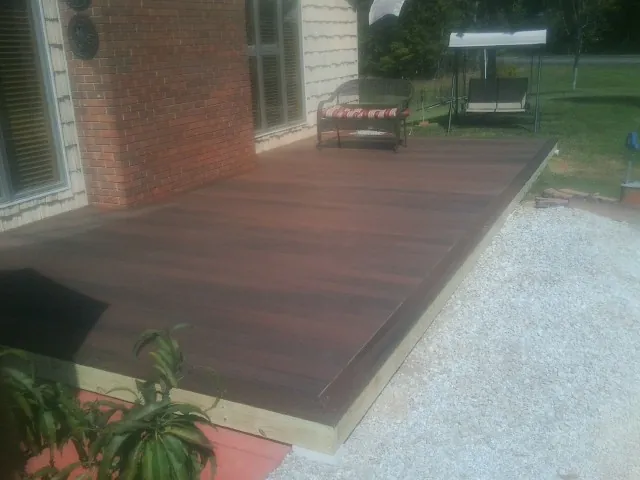 Freshly stained wood deck built against a brick home in Sandwich