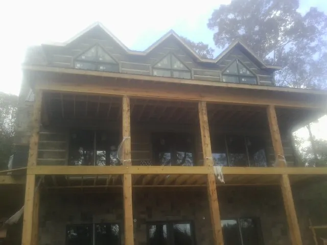 Dormers and porch framing on a large log home under construction — Roof Coating work by our crew in Sandwich
