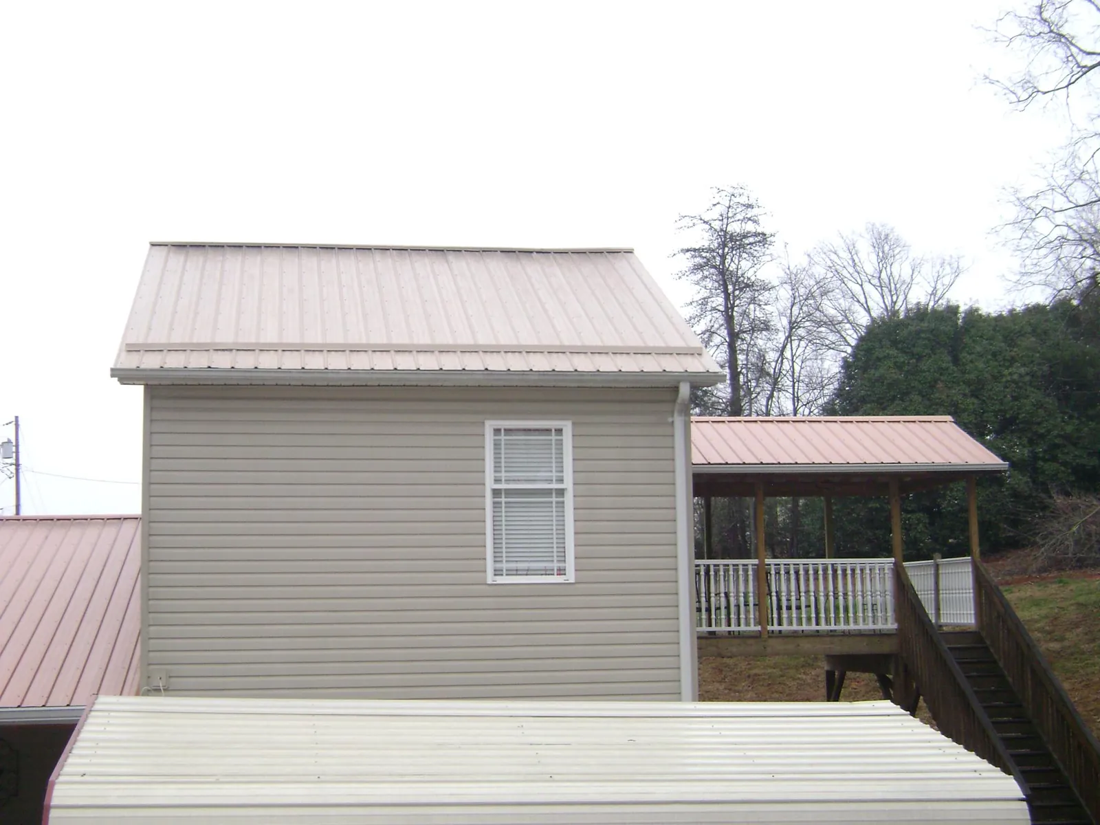 Tan metal roofs on a two story addition and attached porch, from a Roof Replacement job in Sandwich