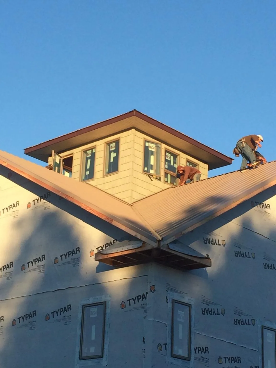 Roofers working around a rooftop cupola on a new metal roof at sunset — Roof Waterproofing in Sandwich by Roofing Brothers